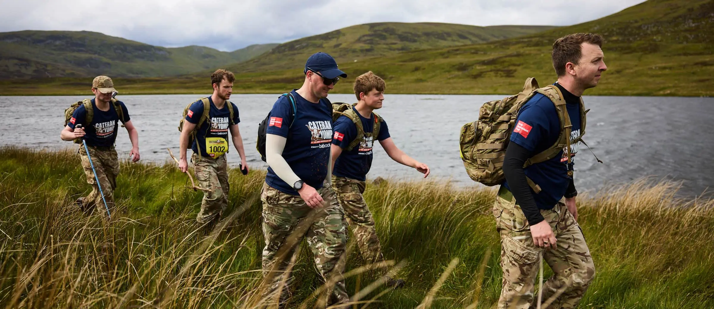 Team of young people trekking across a glen by a lake in Perthshire during the Cateran Yomp